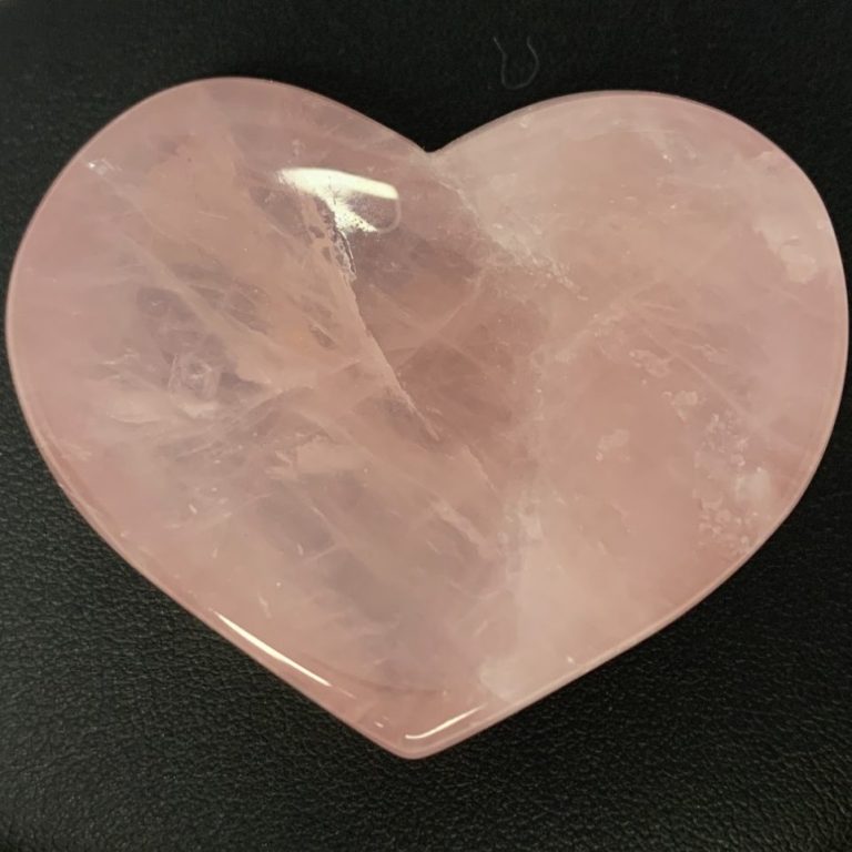Cœur d’énergie et d’amour Cœur en quartz rose poli sur fond noir.